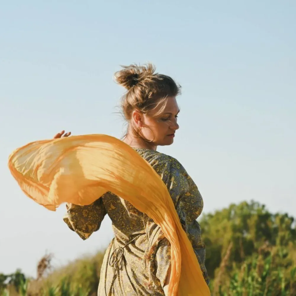 Лора Лански на фоне природы с развевающимся шарфом, символ лёгкости и внутренней свободы